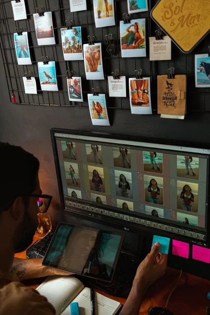 A neat workspace featuring a sketchpad with wireframes, a smartphone, and a keyboard on a wooden desk.